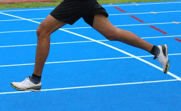 Legs of fast runner runs into the blue in athletics track