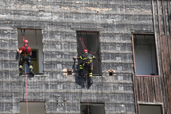 Firefighters climbing a wall of a house during the fire drill