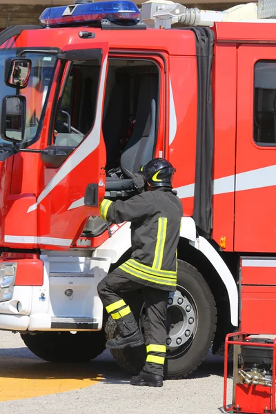 Firefighters in action jump down quickly from the fire engine du