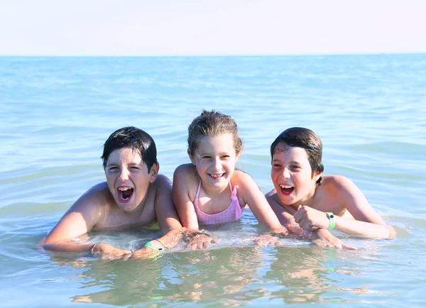 Three young brothers playing in the water of the sea