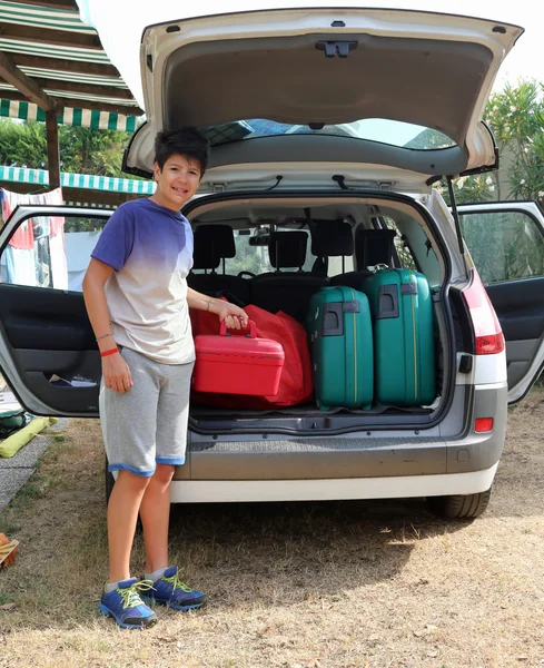 Boy helps load the trunk before leaving for a long journey