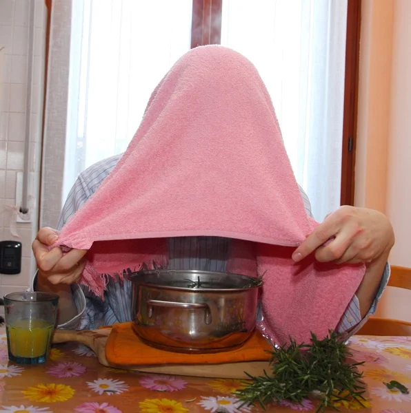 Man with towel breathe balsam vapors to treat colds