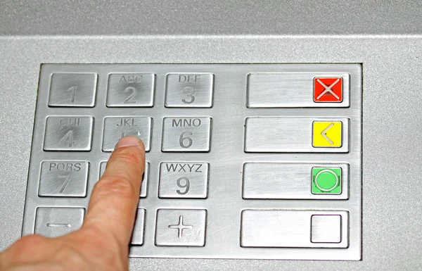Adult hand typing the secret code in the keyboard of an ATM to w