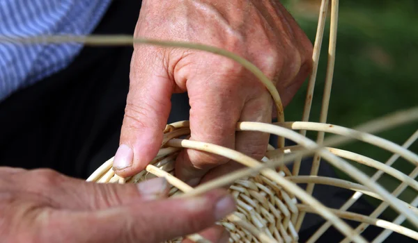 Old craftsman hands who works the cane to make a wicker basket