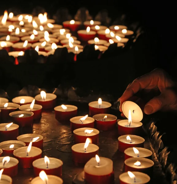 Elderly faithful hand lights a candle