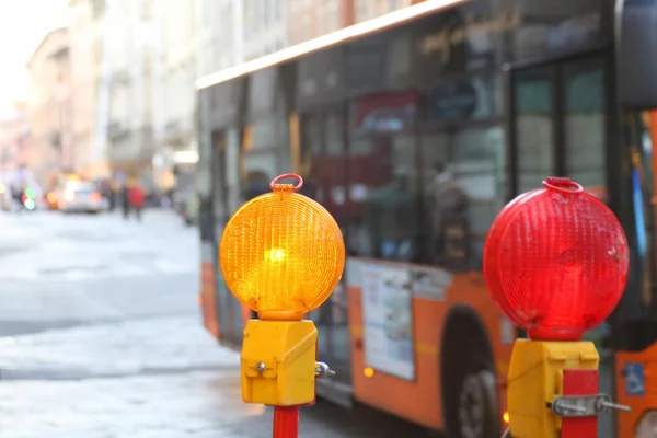 Yellow and red lamps in roadworks in the city with a bus