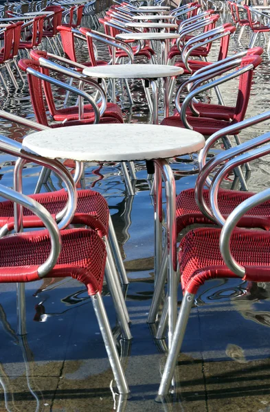Venice, chairs of the outdoor cafes with water at high tide