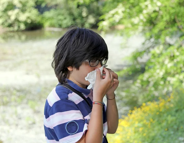 Boy with pollen allergy with handkerchief in hand