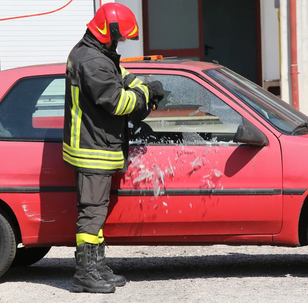 Fireman while breaking the glass of a car with a special equipme