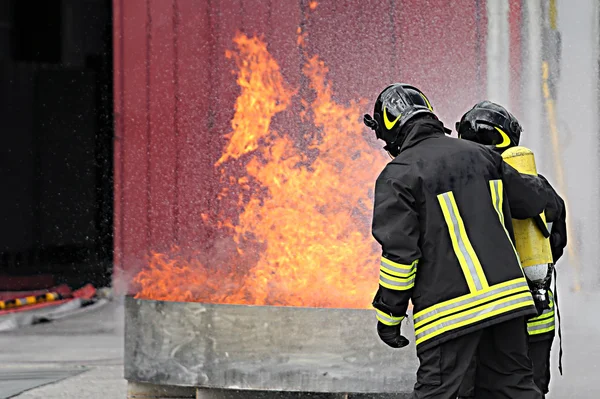 Two firefighters with oxygen bottles off the fire