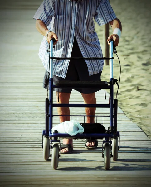 Elderly man walking with Walker on the beach