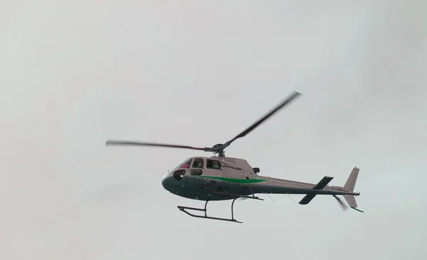 Civil helicopter flies in the sky and carries tourists
