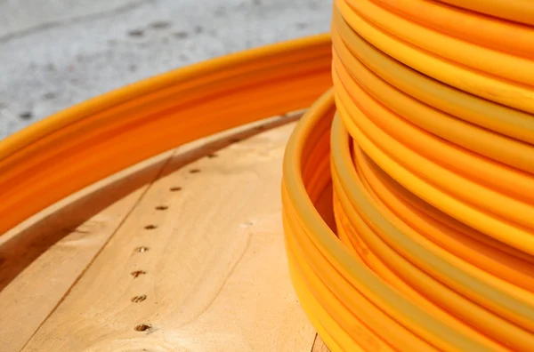 Coils of orange plastic pipes for the installation of undergroun