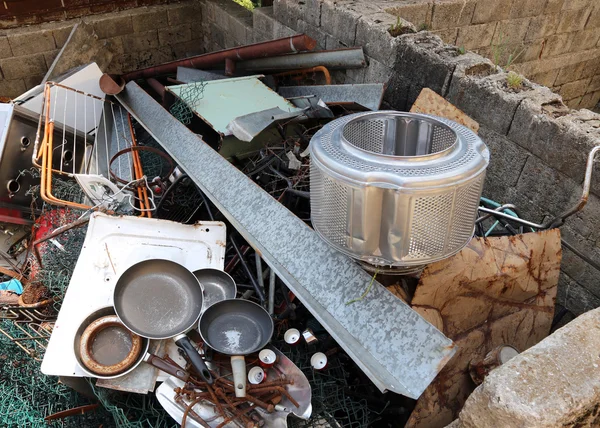 Old pans and washing machine basket in waste landfill