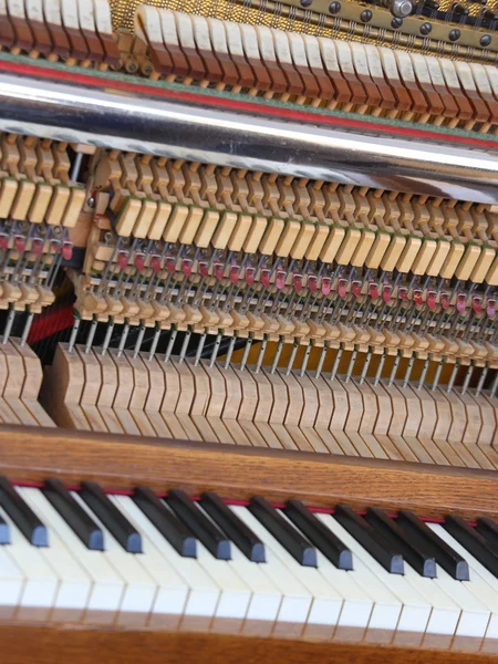 Inside of a piano with little hammer and strings