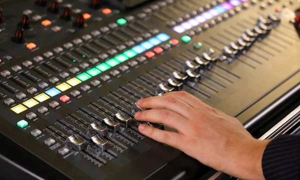 Hand and potentiometers and sound equalizer  during a rock conce