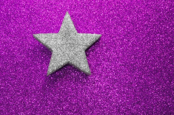 Lone silver star silver on glitter material on purple background