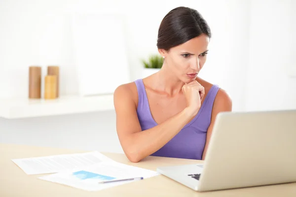 Hispanic woman wondering while working on laptop