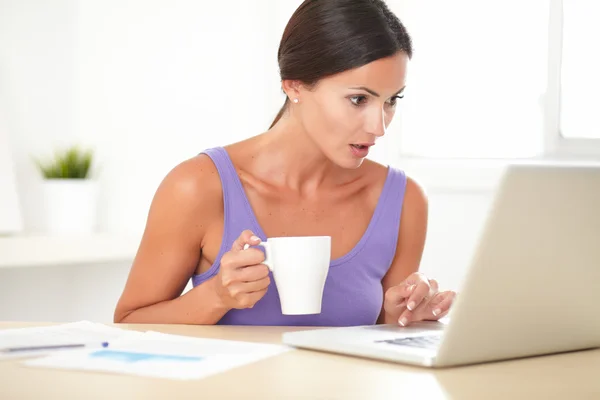 Shocked woman browsing the web on her laptop