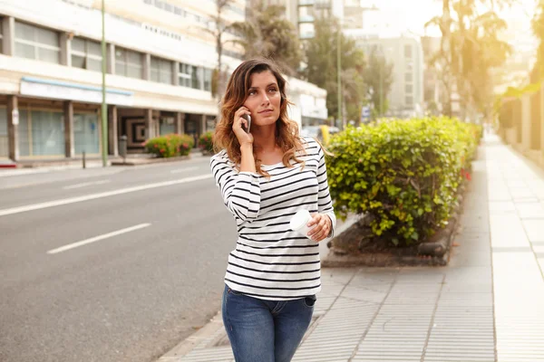 Young woman speaking on mobile phone while walking