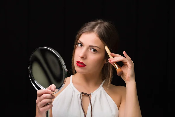 Woman with a mirror and makeup brush