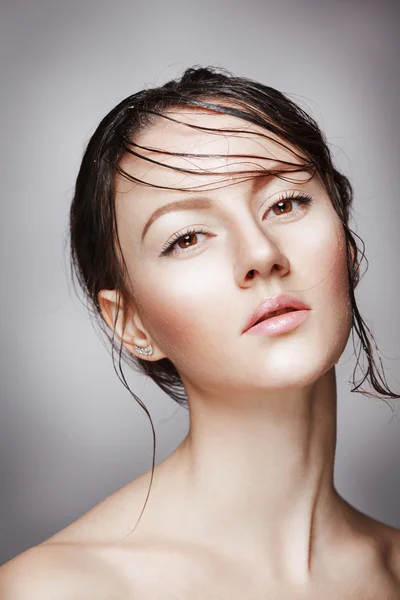 Portrait of young beautiful nude woman with wet shining  makeup on grey background