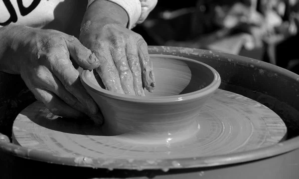 A potters hands working clay on potter\'s wheel