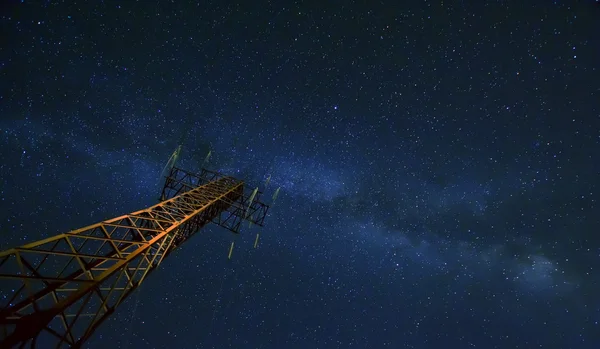 Power lines and tower against night sky with stars and milky way galaxy