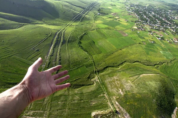 Human hand pointing to a beautiful view of the village in Armenia from a hot air balloon