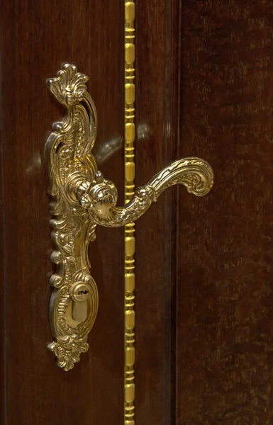 Classical style golden door handle on brown wooden door