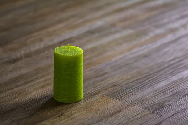 Green candle on the wooden floor