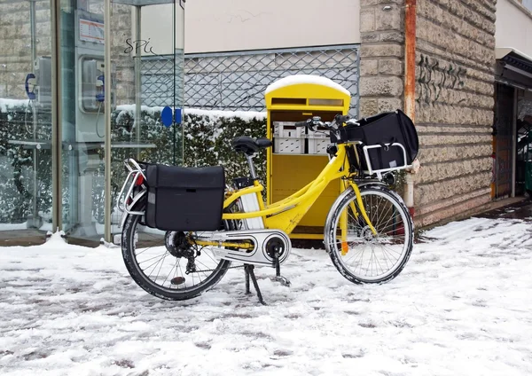 Postal delivery in bike, winter under the snow