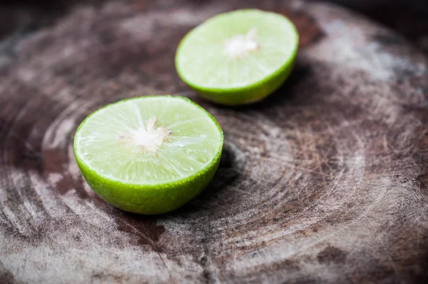 Green Lemon cut on wooden background