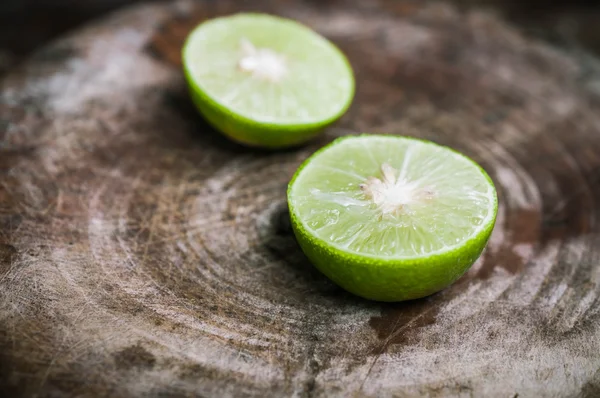 Green Lemon cut on wooden background