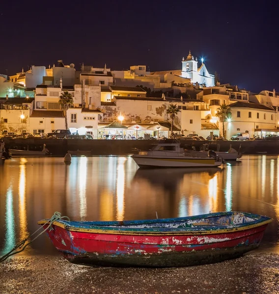 Old sea town of Ferragudo in lights at night. Boats in the foreground.