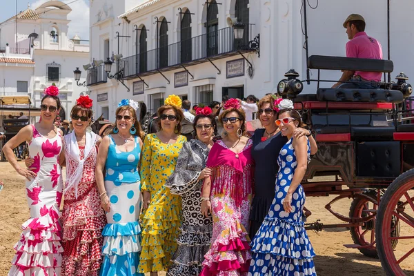 El ROCIO, ANDALUCIA, SPAIN - MAY 22: senoritas Girls pose for photographers outside the church. 2015 The annual religious festival. In the background, the rider in the carriage with a horse. It is one