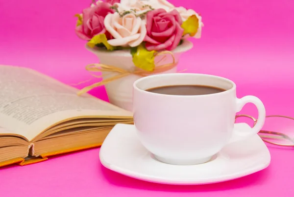 Cup of coffee with book isolated on pink background