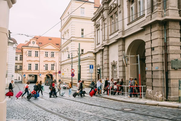 People cross the tram tracks on the street Malostranske namesti