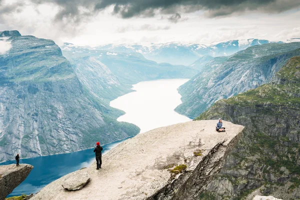 Young People Are Photographed Standing On A Rock Trolltunga - Troll Tongue