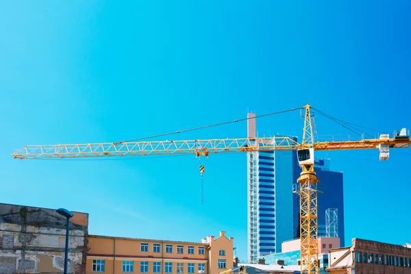 Construction Crane On Background Of New Modern Skyscraper And Ol