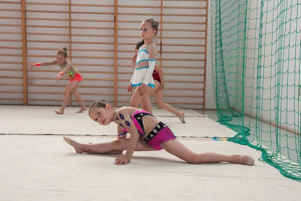 The competition of art gymnastics. A group of small girls practicing before the competition