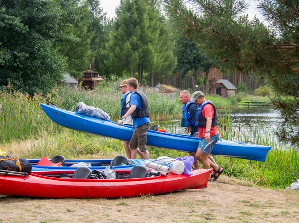 Men carrying a  loaded kayak over an obstacle