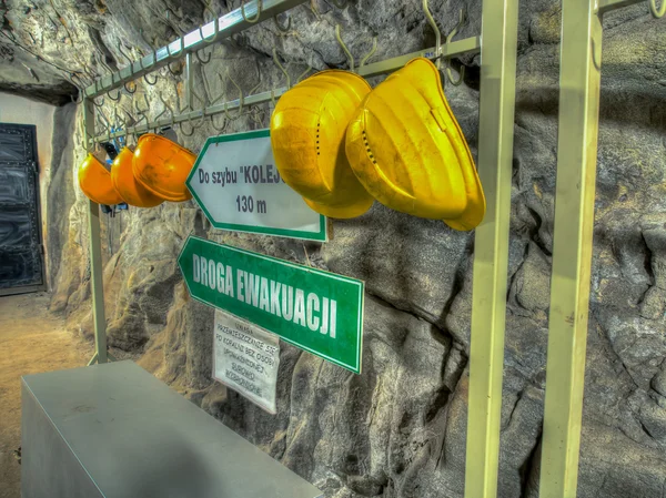 Yellow protective hard hats hanging in front of an entry into a pit of coal mine.