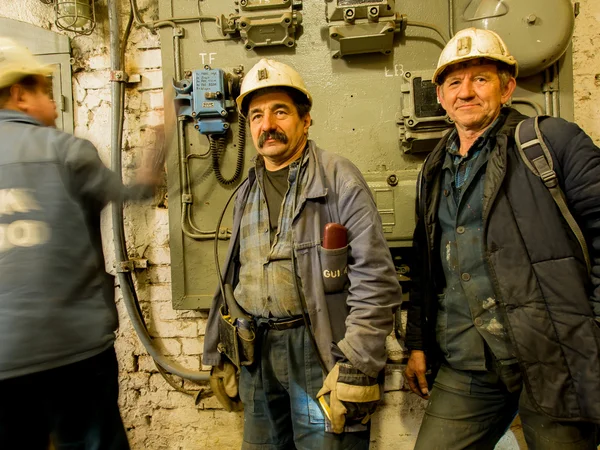 Employees of a coal mine wearing working clothes and waiting for an elevator.