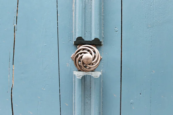 Old style sliver door handle and blue woody door close up