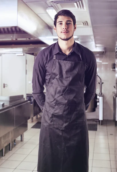 Young chef or waiter wearing black apron isolated