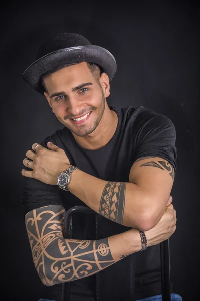 Young man with black bowler hat and tattoos