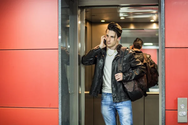 Handsome young man in elevator using cell phone