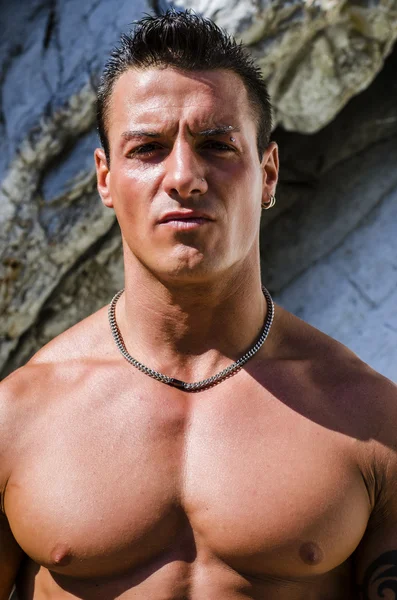 Attractive young muscle man shirtless against white rocks