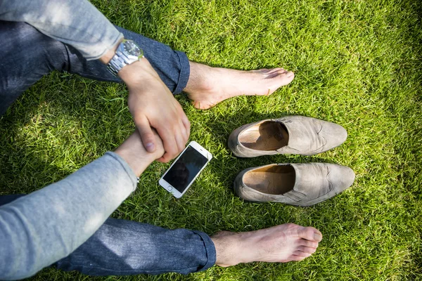 Barefoot man sitting on grass